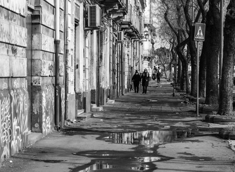 Captured in Catania, Sicily, this monochromatic street scene showcases urban life and architecture.