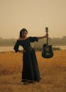 Woman in Black Holding Acoustic Guitar Outdoors