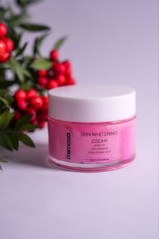 Pink skincare cream jar with red berries against a soft background.
