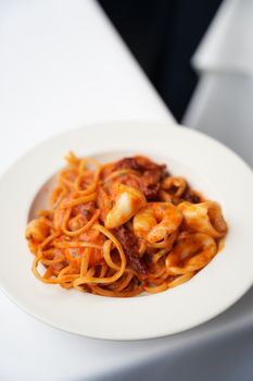 Close-up of a plate of spaghetti with tomato seafood sauce, featuring shrimp.