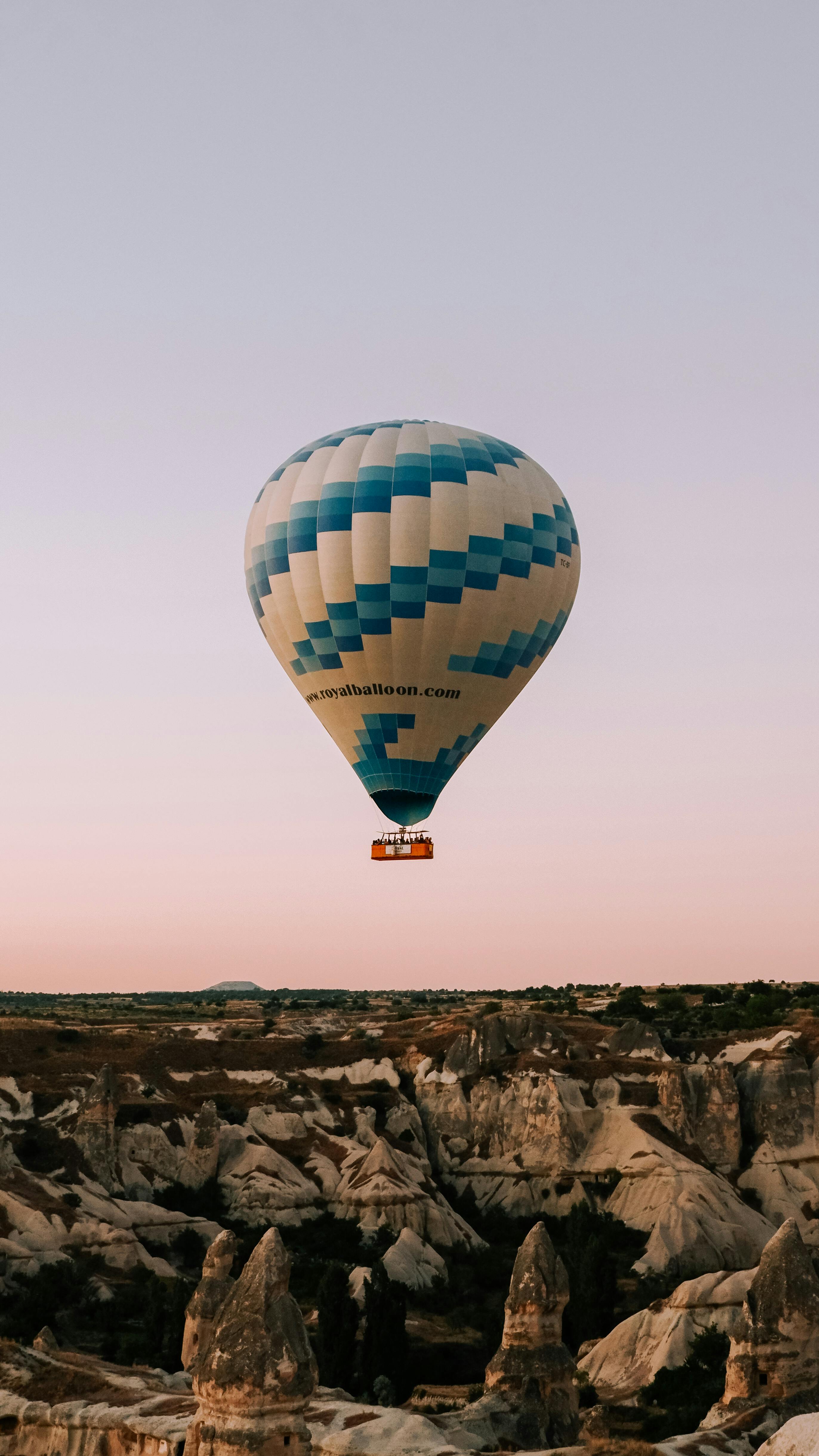 Free Beautiful view of a hot air balloon soaring over Cappadocia's unique rock formations at sunrise. Stock Photo