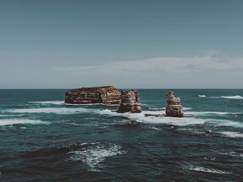 Formação De Rocha Marrom No Mar Sob O Céu Azul