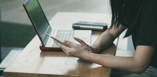 Mujer Sentada En Una Silla Junto A La Mesa Mientras Usa El Teléfono