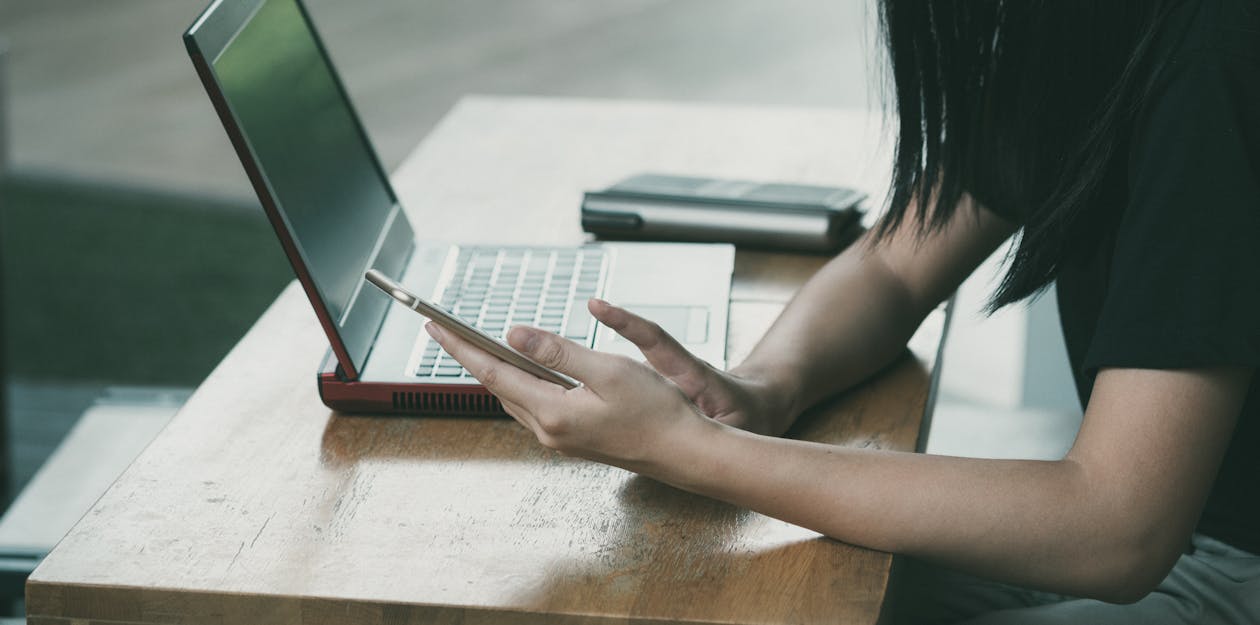 Wanita Duduk Di Kursi Di Samping Meja Saat Menggunakan Telepon