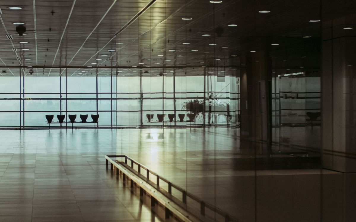 A calm and empty airport terminal in Singapore with a reflective glass facade and soft lighting.