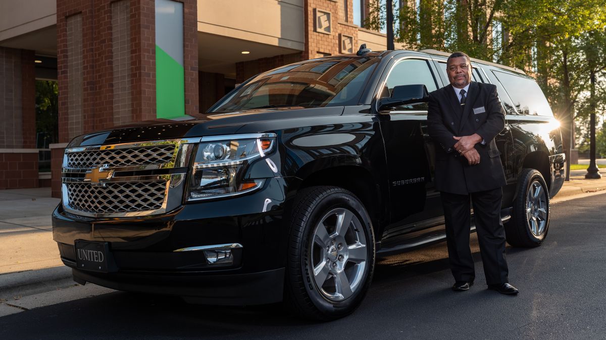 Chauffeur standing beside a black SUV providing executive transfer service