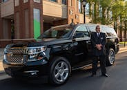 Chauffeur Standing by Luxury Black SUV Outdoors