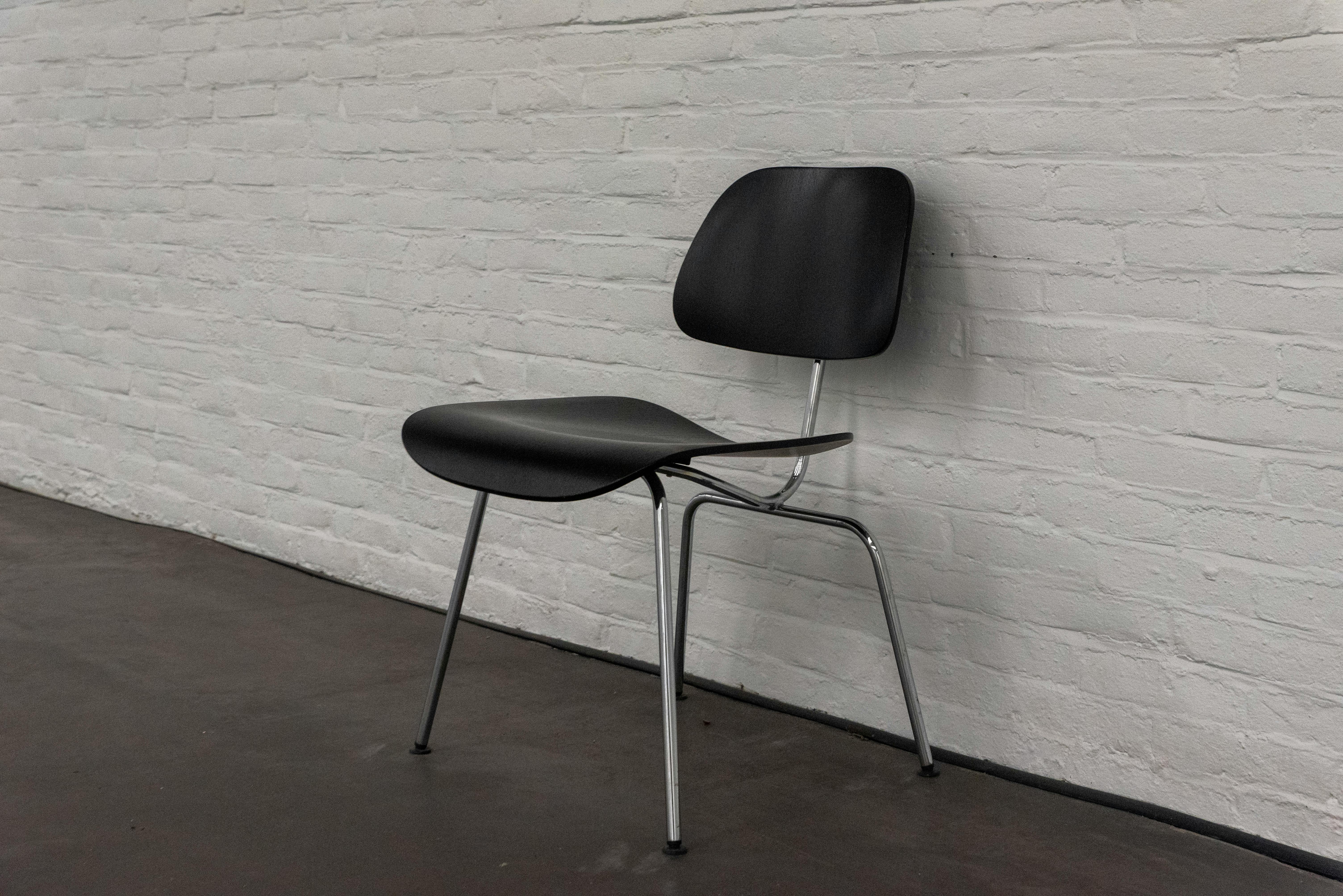 Gratuit Chaise noire élégante aux pieds chromés, placée devant un mur de briques blanches dans un décor minimaliste. Photos
