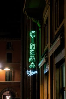 Night street scene with a neon cinema sign glowing vibrantly in an urban setting.