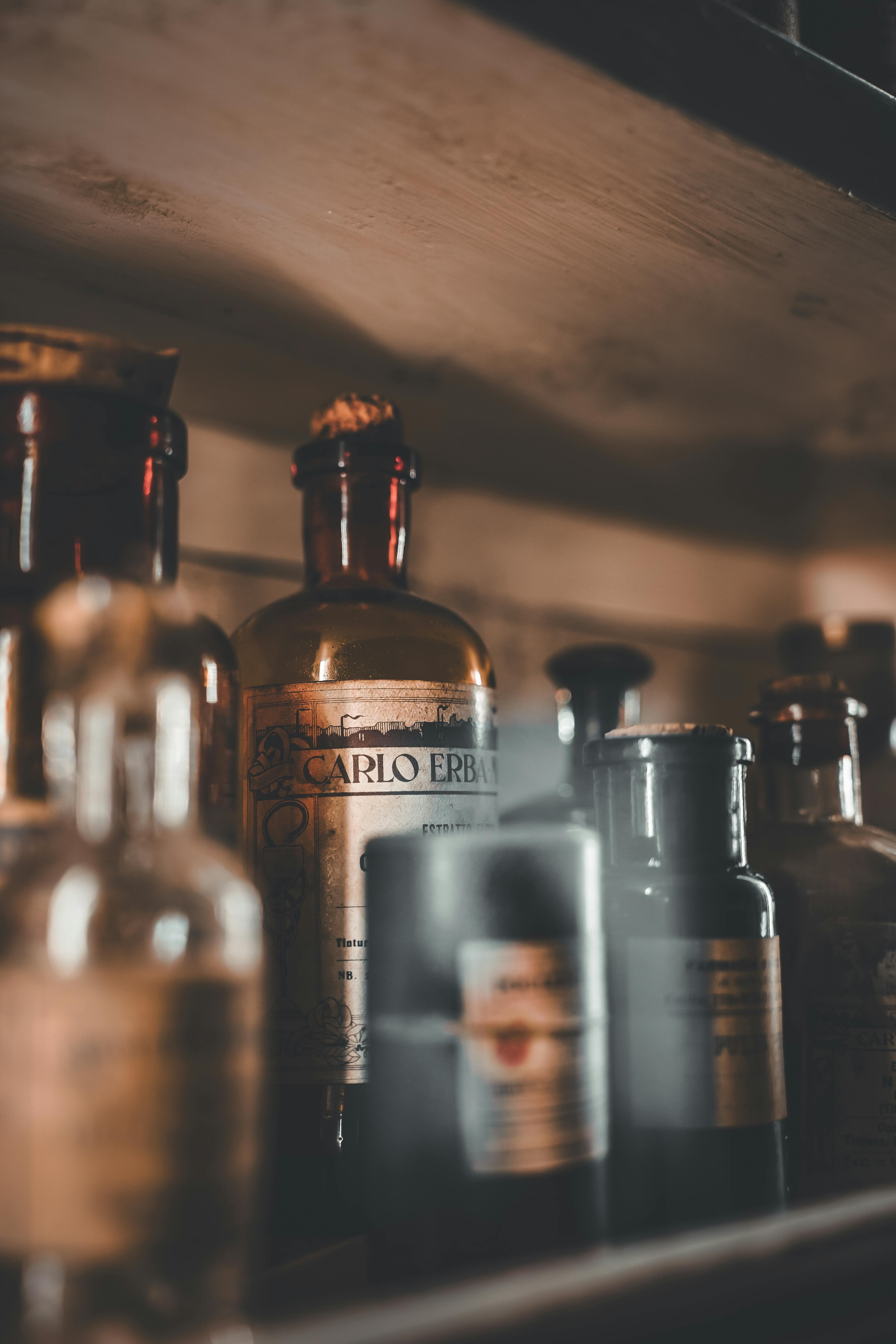 無料 薄暗い照明の下で木製の棚に並べられたビンテージの薬瓶のコレクション。 写真素材