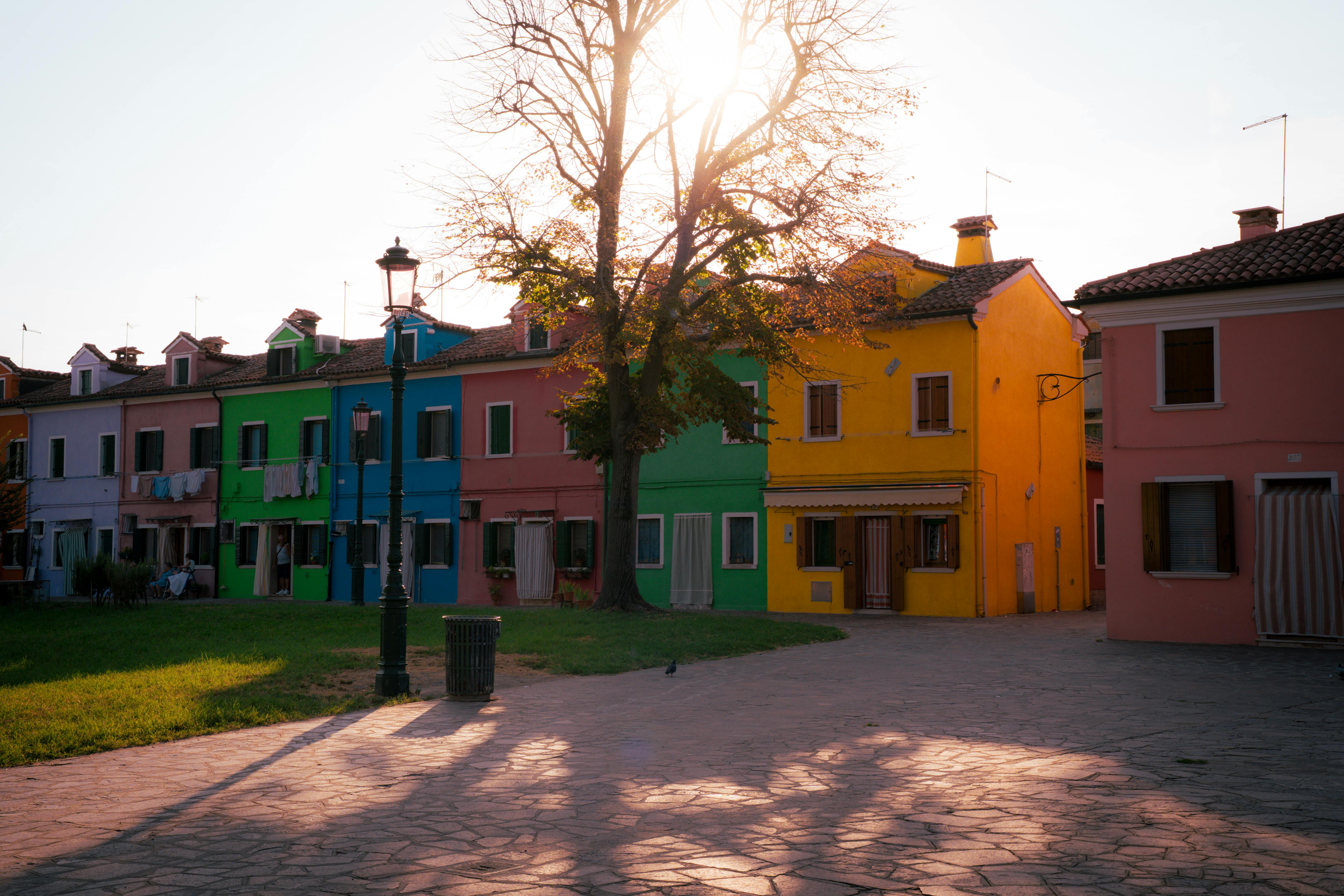 бесплатная Яркие разноцветные дома на острове Бурано в Венеции на закате, создающие теплую и уютную атмосферу. Стоковое фото
