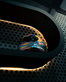 A racing helmet on a perforated metal shelf with modern lighting.