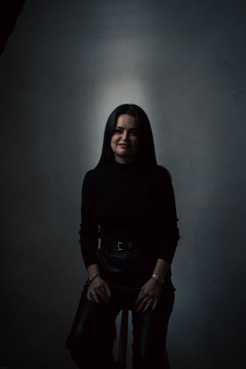 Free Captivating portrait of a woman in a dark, moody studio setting. Stock Photo