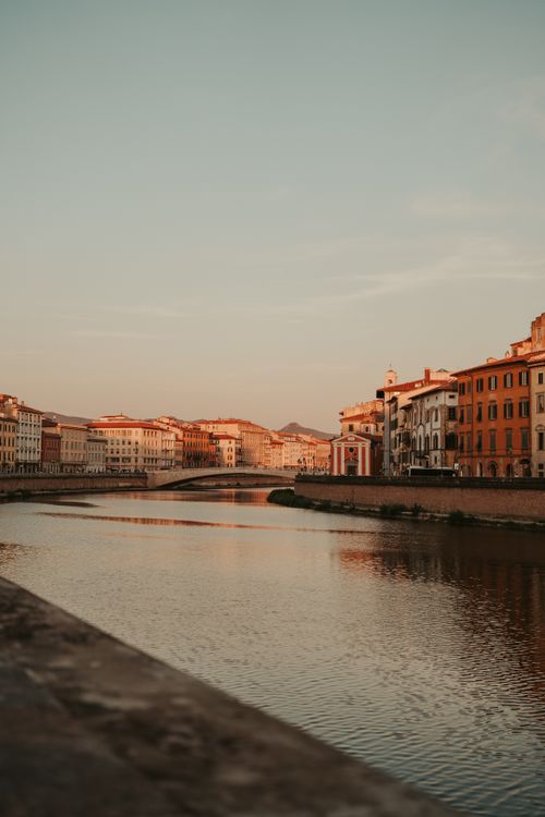 Free Scenic view of Arno River with historic buildings in Florence at sunset, showcasing serene beauty. Stock Photo