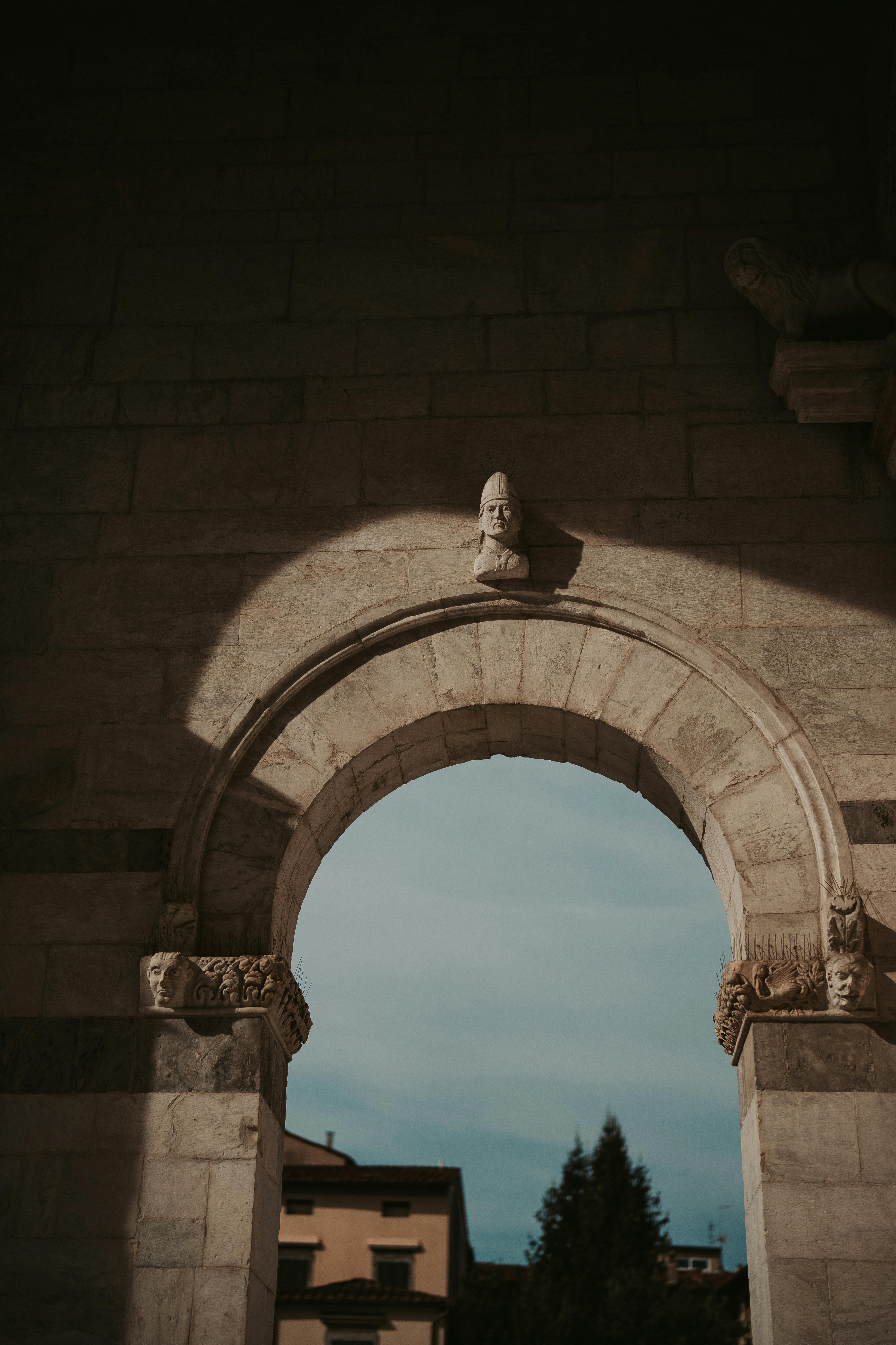 Zadarmo Krásne osvetlený kamenný oblúk s prepracovanými sochami a historickým architektonickým dizajnom. Fotka z fotobanky