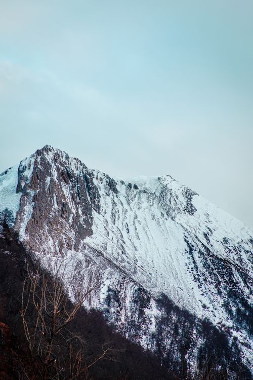 Free Breathtaking view of a towering, snow-capped mountain peak under a cloudy sky. Stock Photo