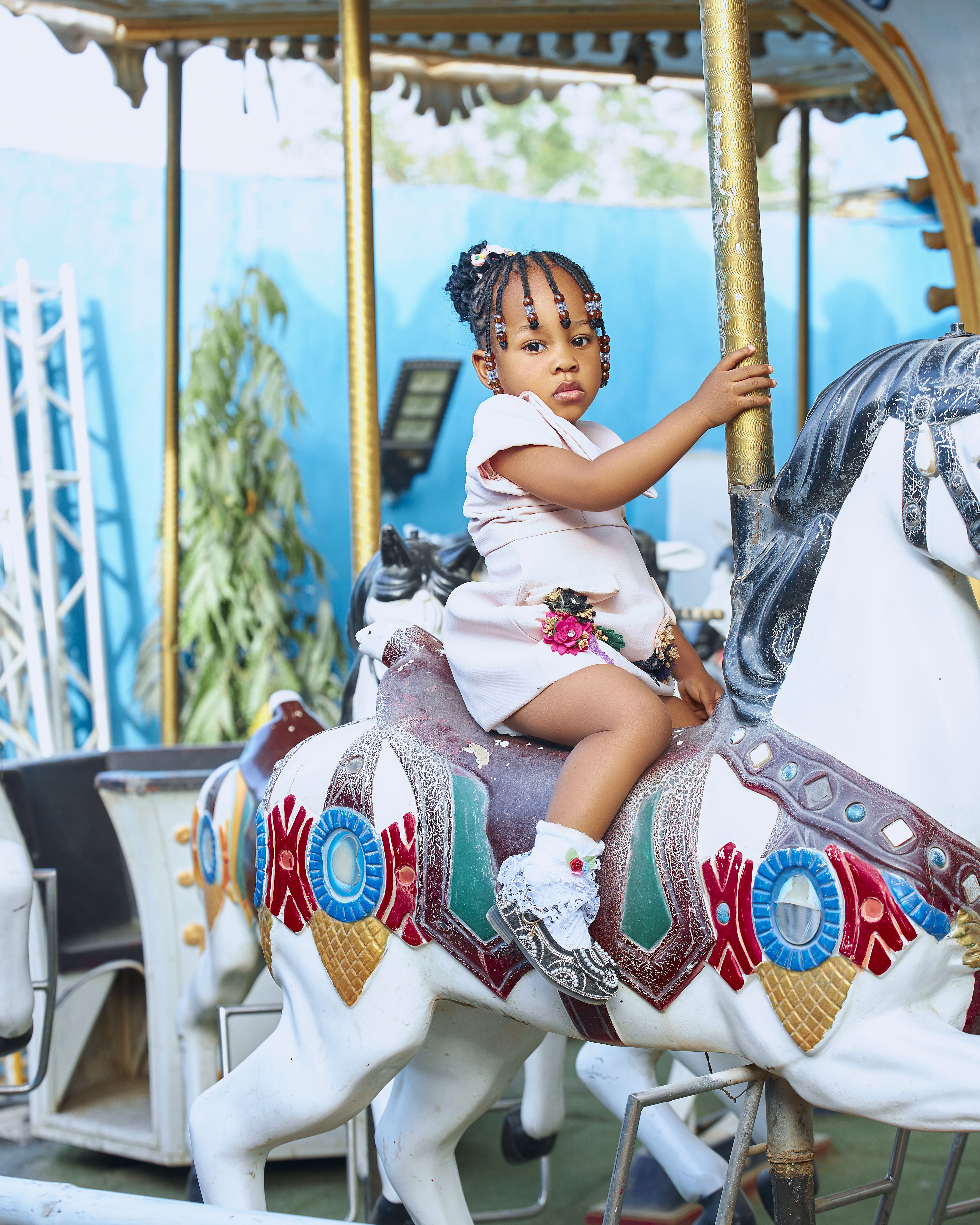 Young girl on a carousel horse at a vibrant amusement park.