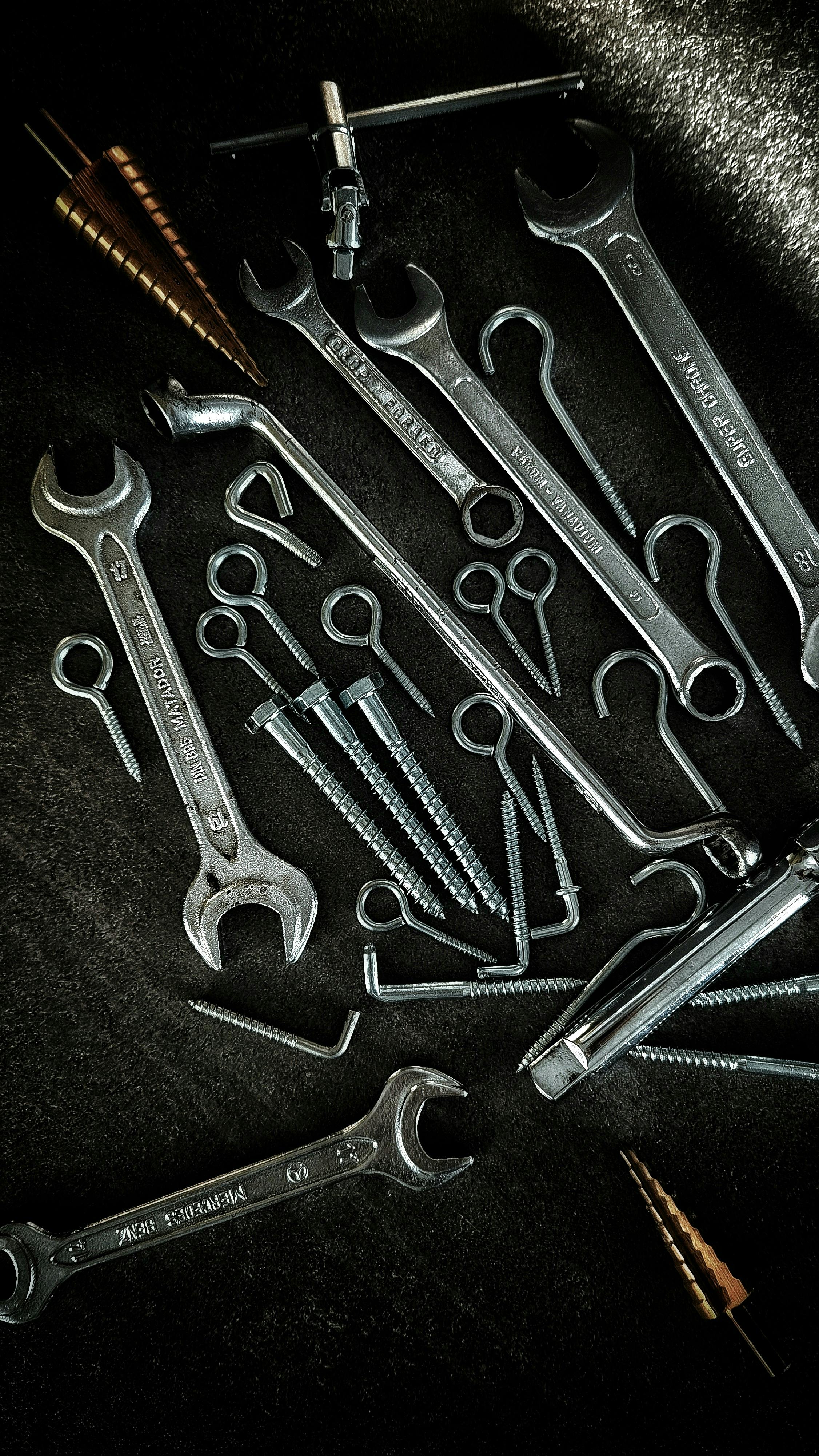 Free A collection of vintage metal tools, including wrenches and screws, laid out on a dark surface. Stock Photo