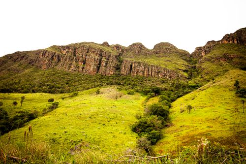 Free Scenic view of lush green hills and rocky formations on a sunny day. Stock Photo