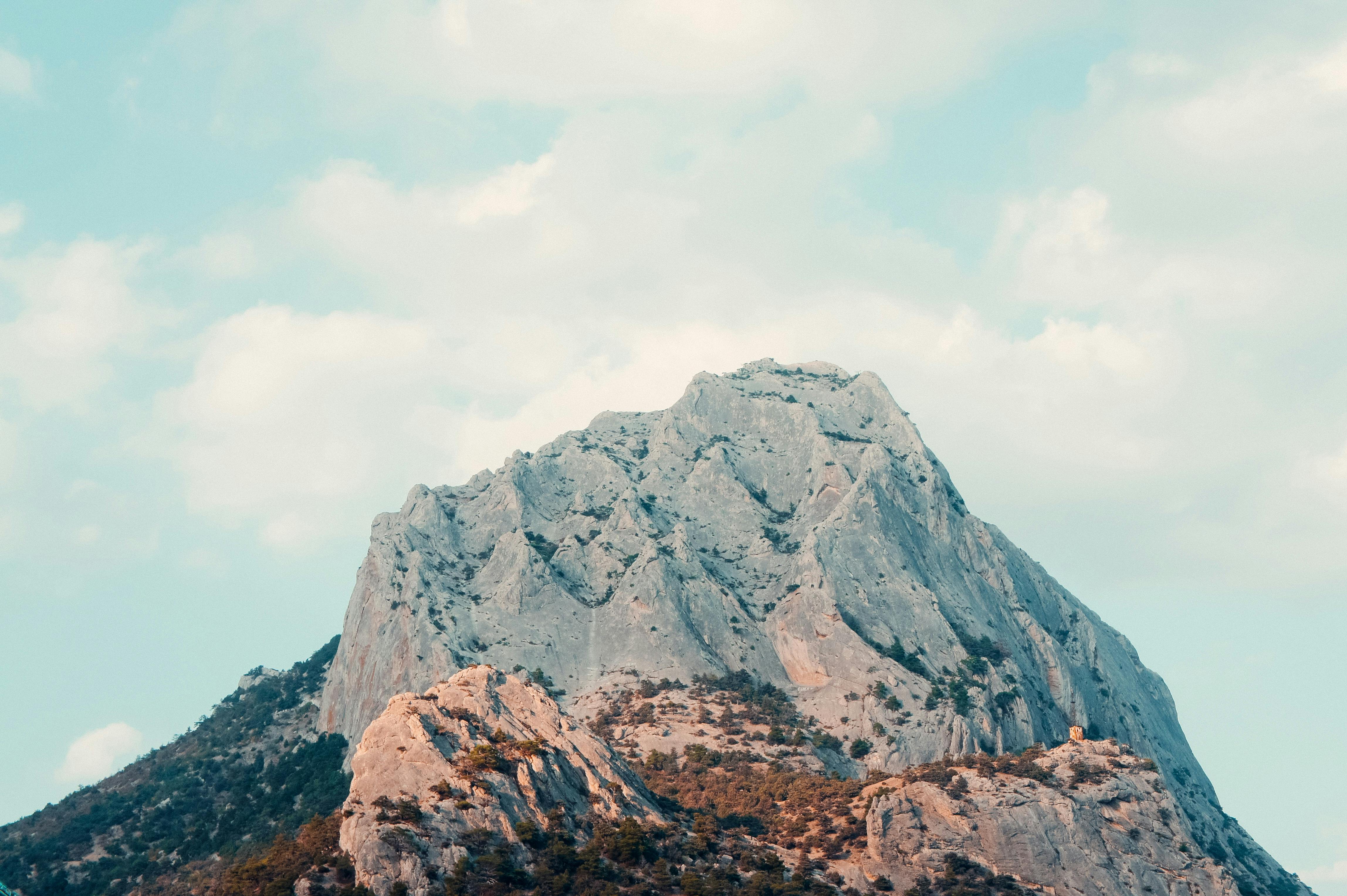 ฟรี ภาพทิวทัศน์อันงดงามของยอดเขาหินสูงตระหง่านตัดกับท้องฟ้าสีฟ้าสดใสที่มีเมฆปุยลอยอยู่ คลังภาพถ่าย