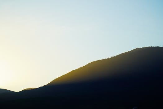 Peaceful silhouette of a mountain with golden sunrise glow.