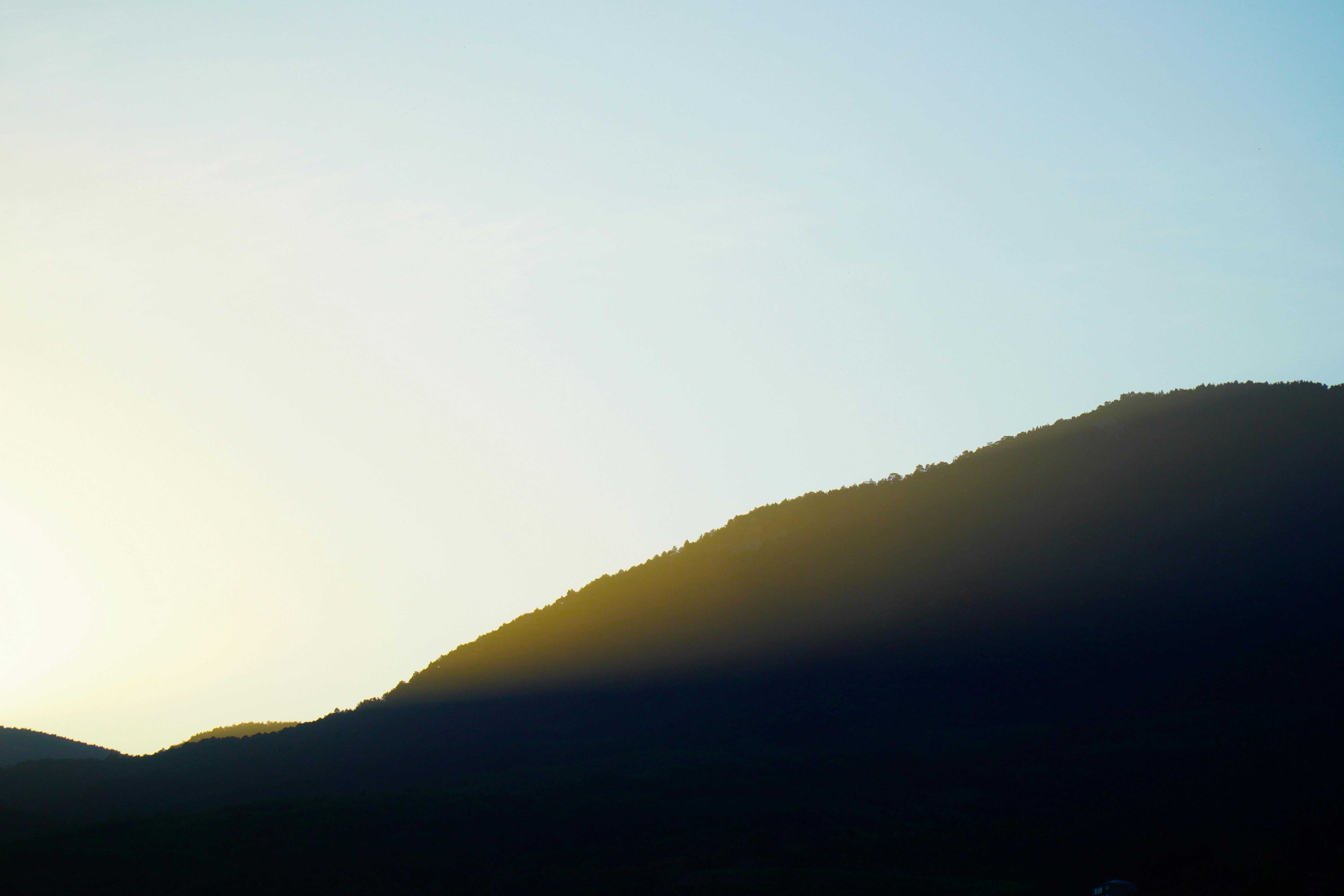 Free Peaceful silhouette of a mountain with golden sunrise glow. Stock Photo