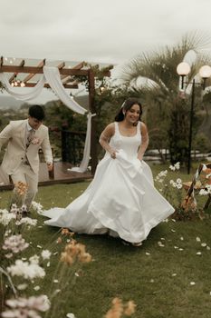 Happy couple running during an outdoor wedding. Captures candid joy and celebration.