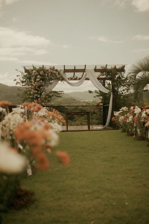 Free A beautiful outdoor wedding ceremony setup with a floral pergola and scenic backdrop. Stock Photo