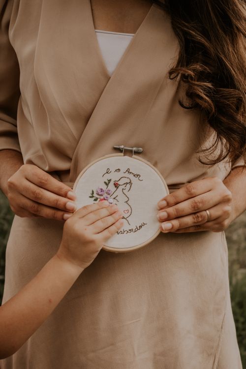 Free A child's hand holding embroidery hoop with heartfelt art and text. Stock Photo