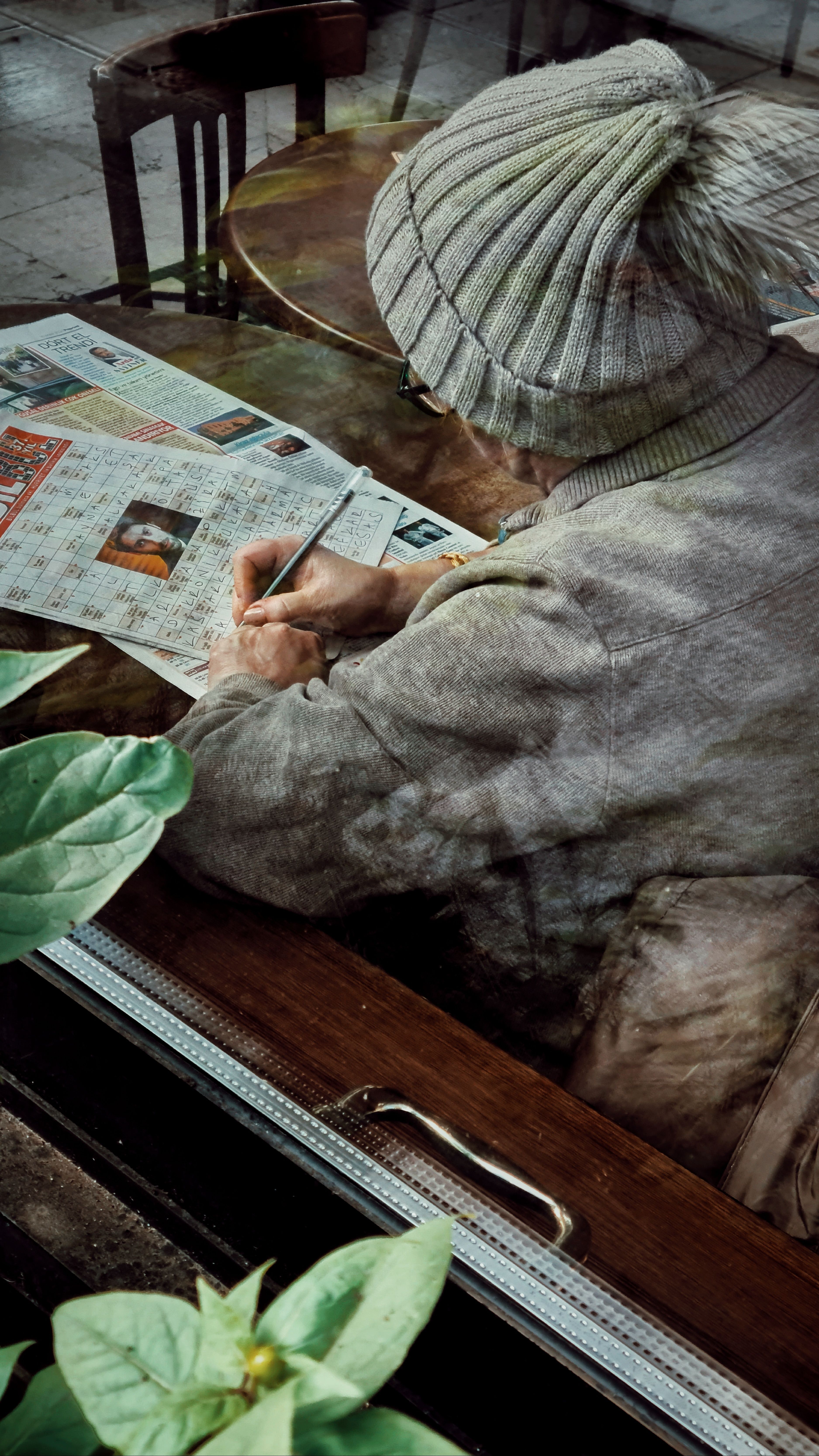 Cozy café scene with an elderly person solving crosswords through the window.