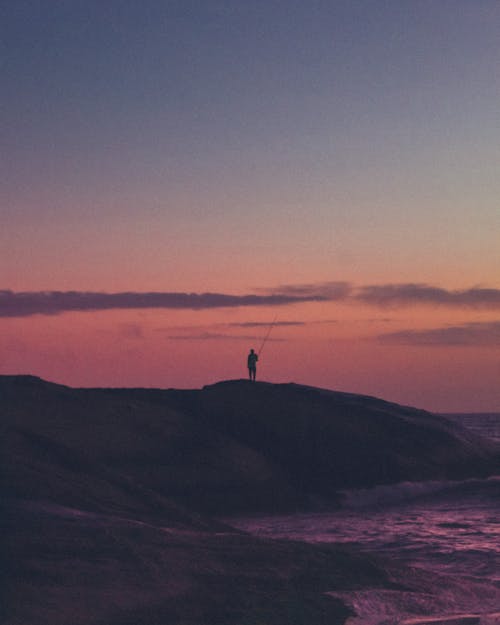 бесплатная Человек, стоящий на острове во время заката Стоковое фото
