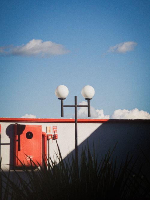 Free Minimalist rooftop with lamp post, red accents, and clear blue sky. Perfect for urban-themed designs. Stock Photo