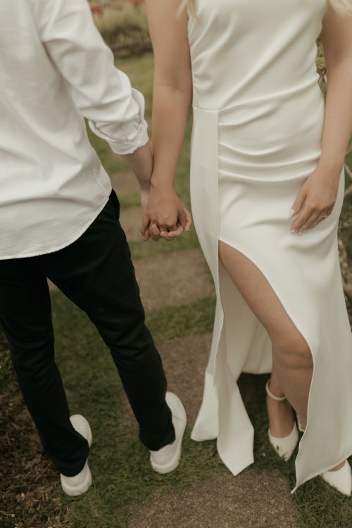 Free A couple in formal attire walks hand in hand, symbolizing love and connection. Stock Photo