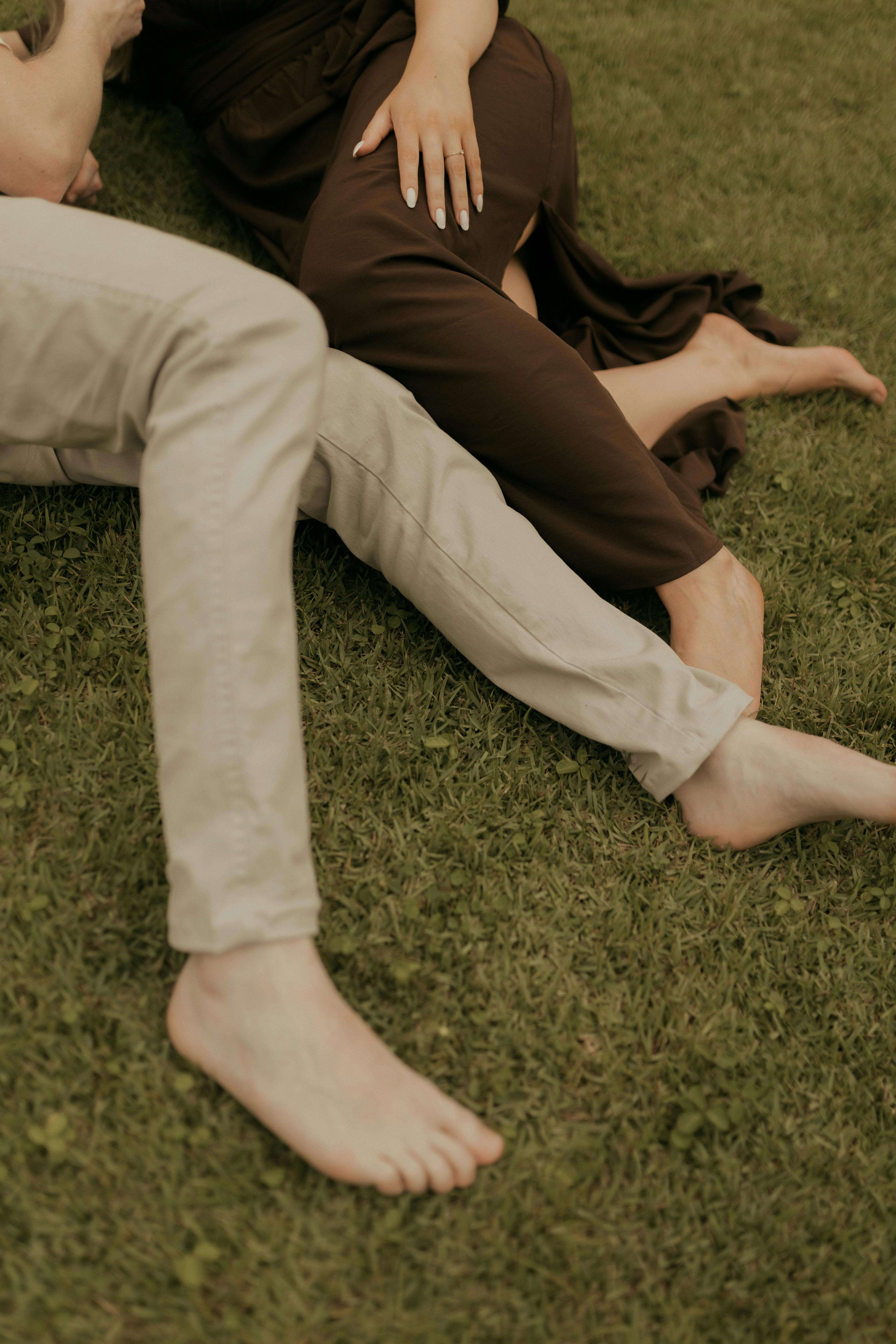 De franc Una parella estirada descalça a l'herba significa relaxació i unió. Foto d'estoc