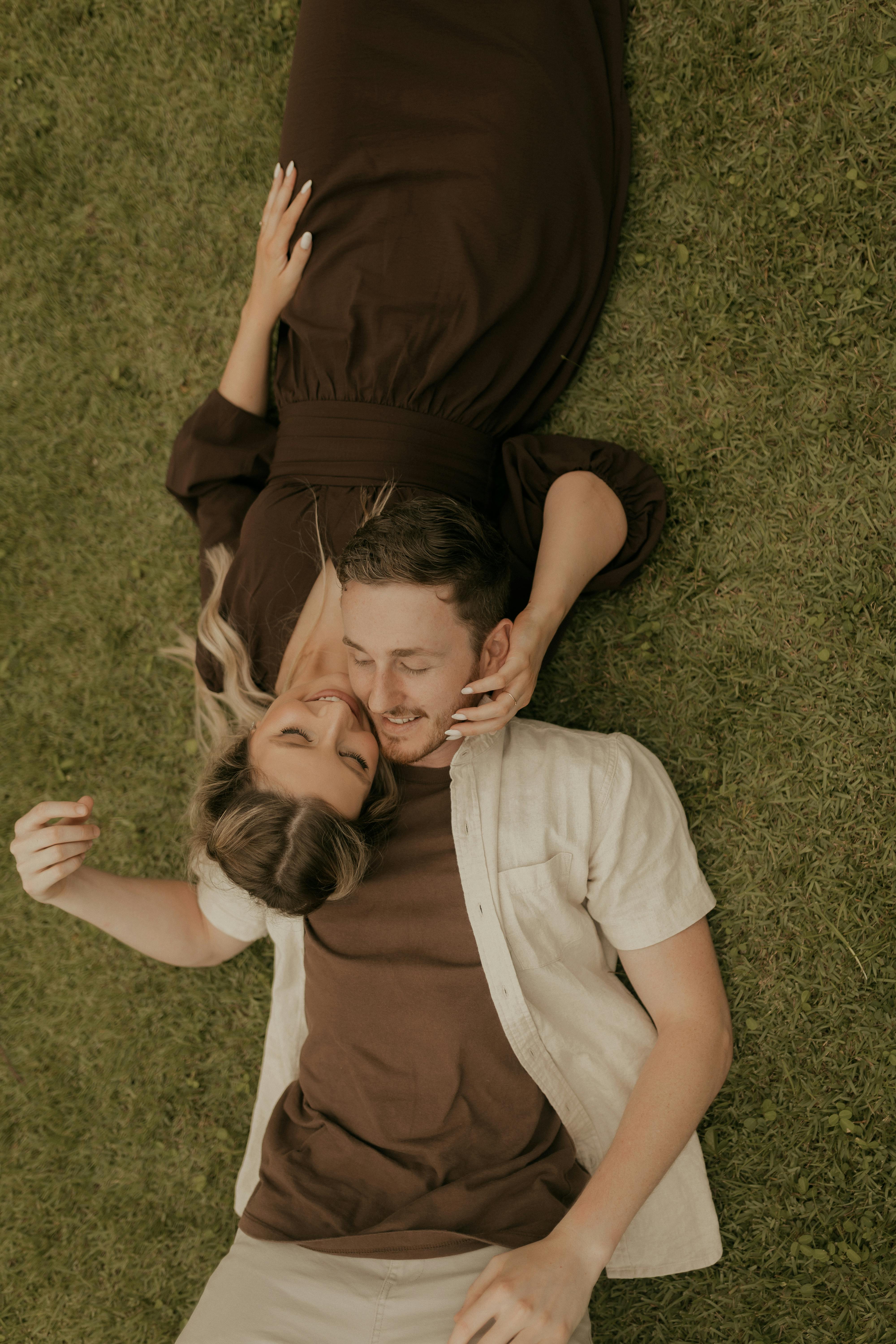 Kostenlos Ein verliebtes Paar liegt auf dem Rasen und genießt gemeinsam einen ruhigen Moment im Freien. Stock-Foto