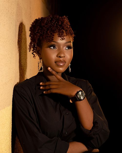 Free Elegant portrait of a young woman with curly hair and chic accessories in warm lighting. Stock Photo