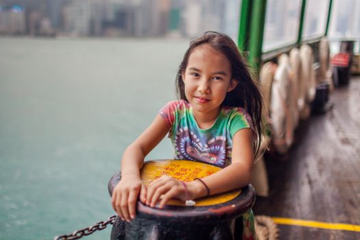 Girl enjoying a scenic ferry ride with Hong Kong skyline views in the background.