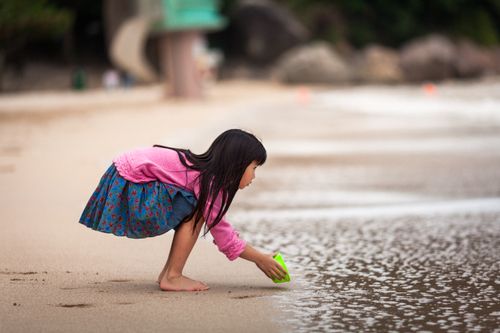 Free A young girl in bright clothing plays by the seashore in New Territories, Hong Kong. Stock Photo