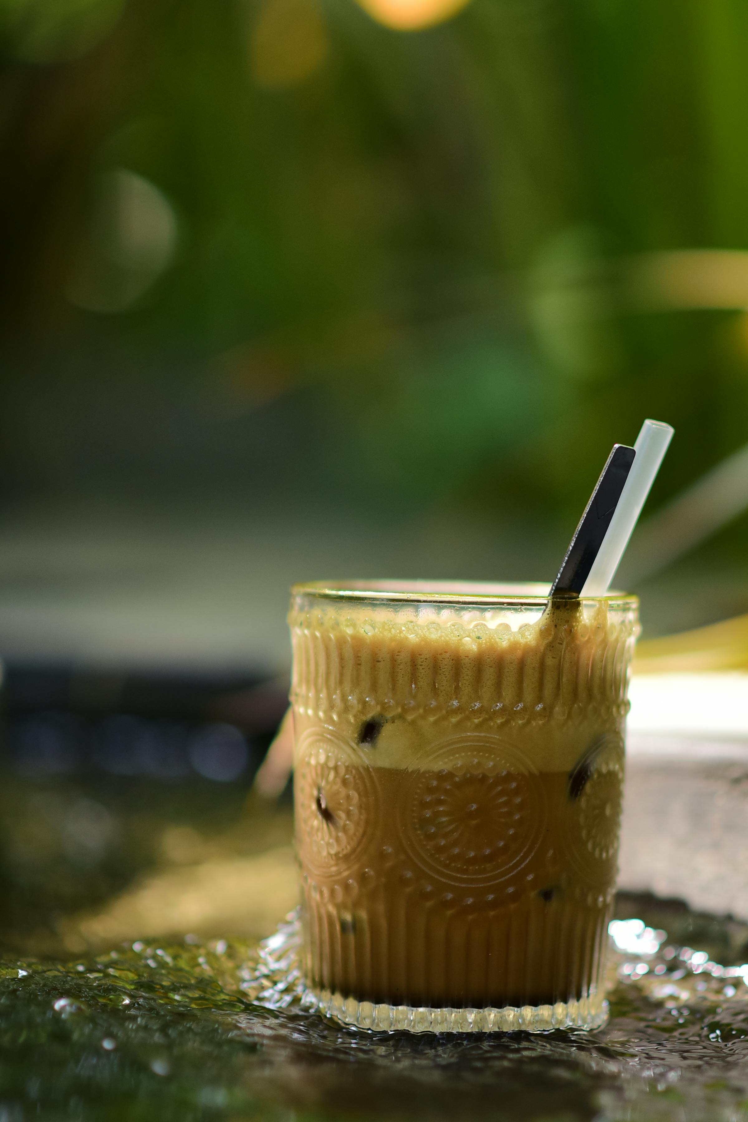 Free Close-up of iced coffee in an ornate glass with straws, set outside in natural light. Stock Photo