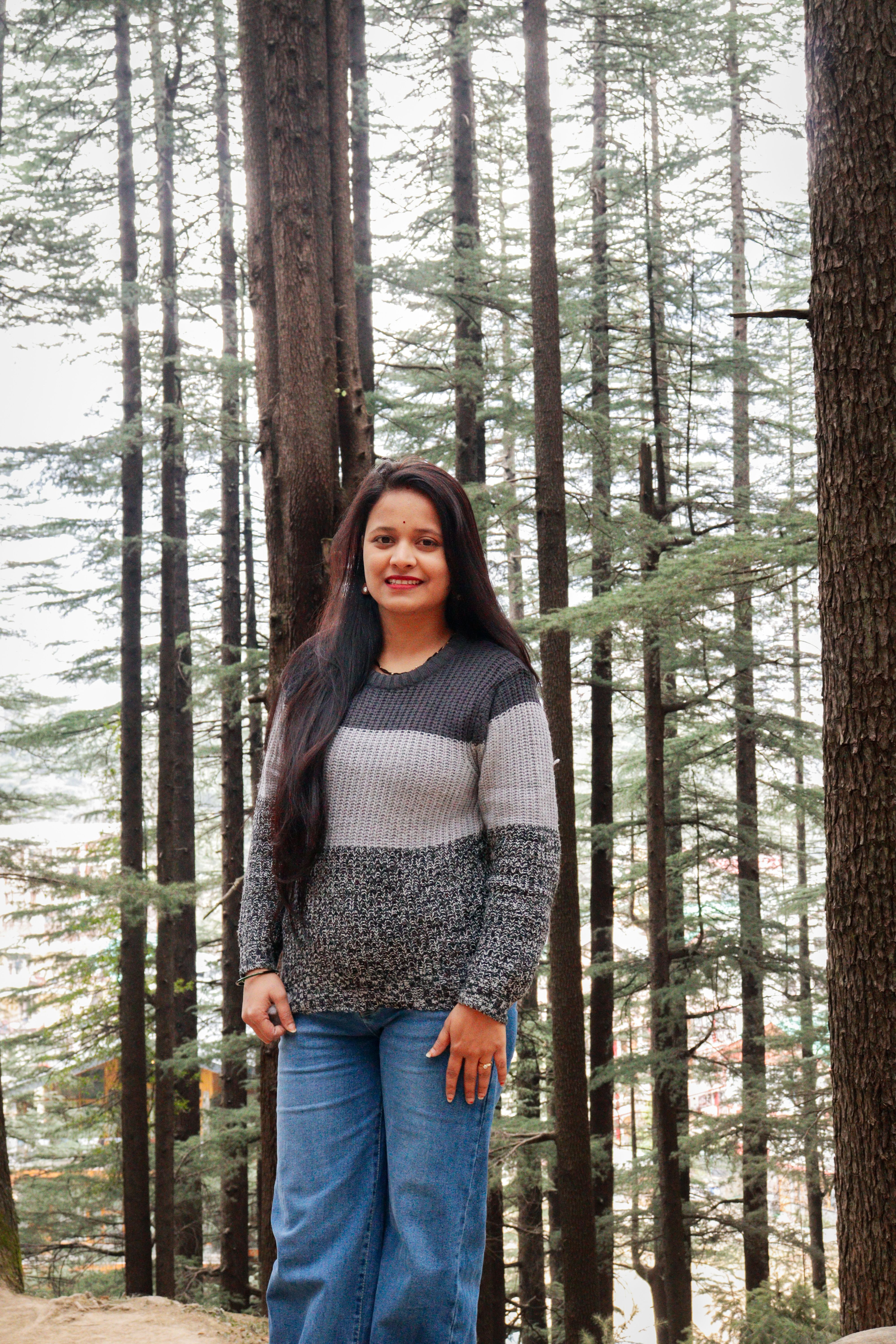 A woman standing in a serene pine forest, enjoying nature and fresh air.