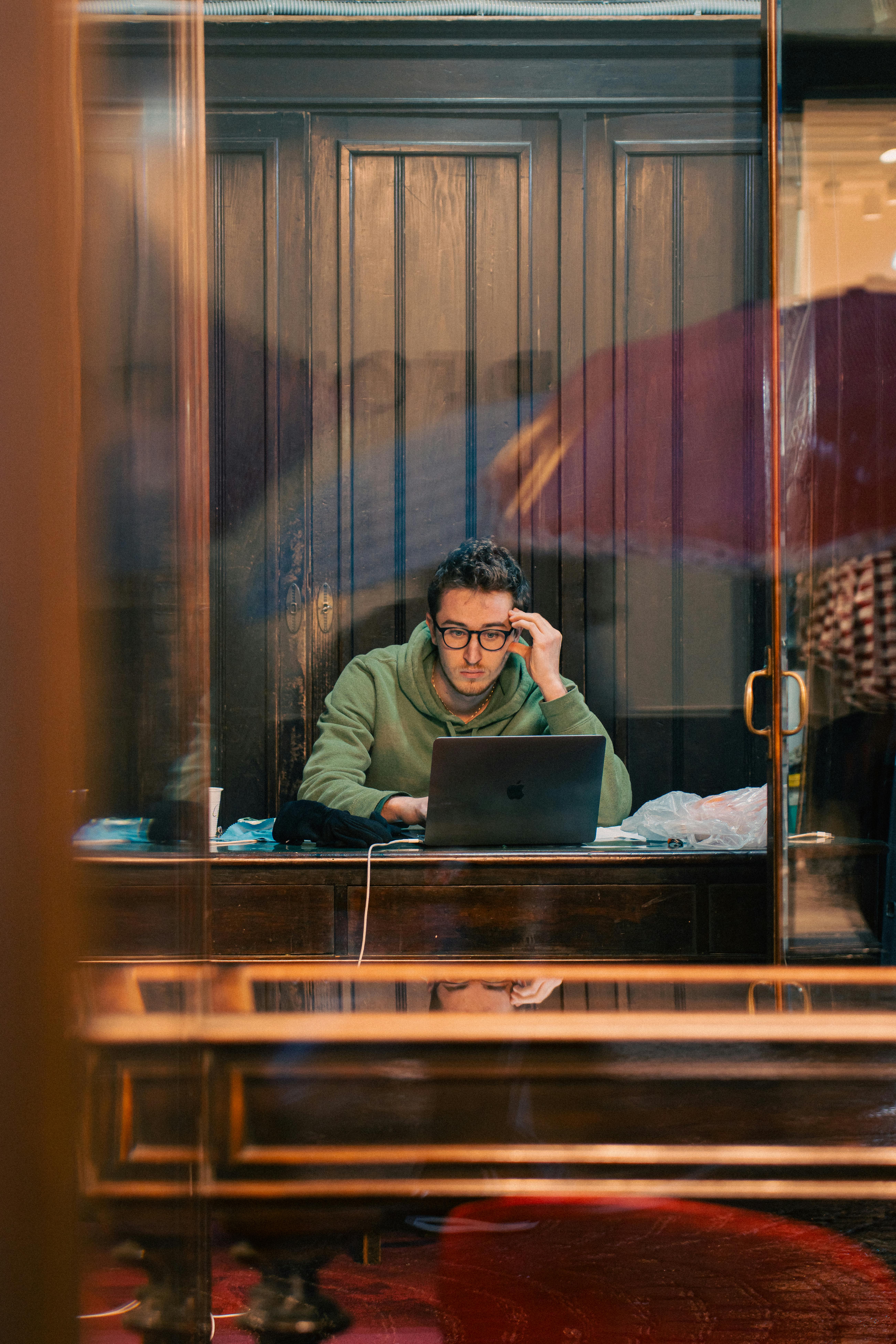 無料 屋内のカフェでノートパソコンに集中して取り組んでいる若者。 写真素材