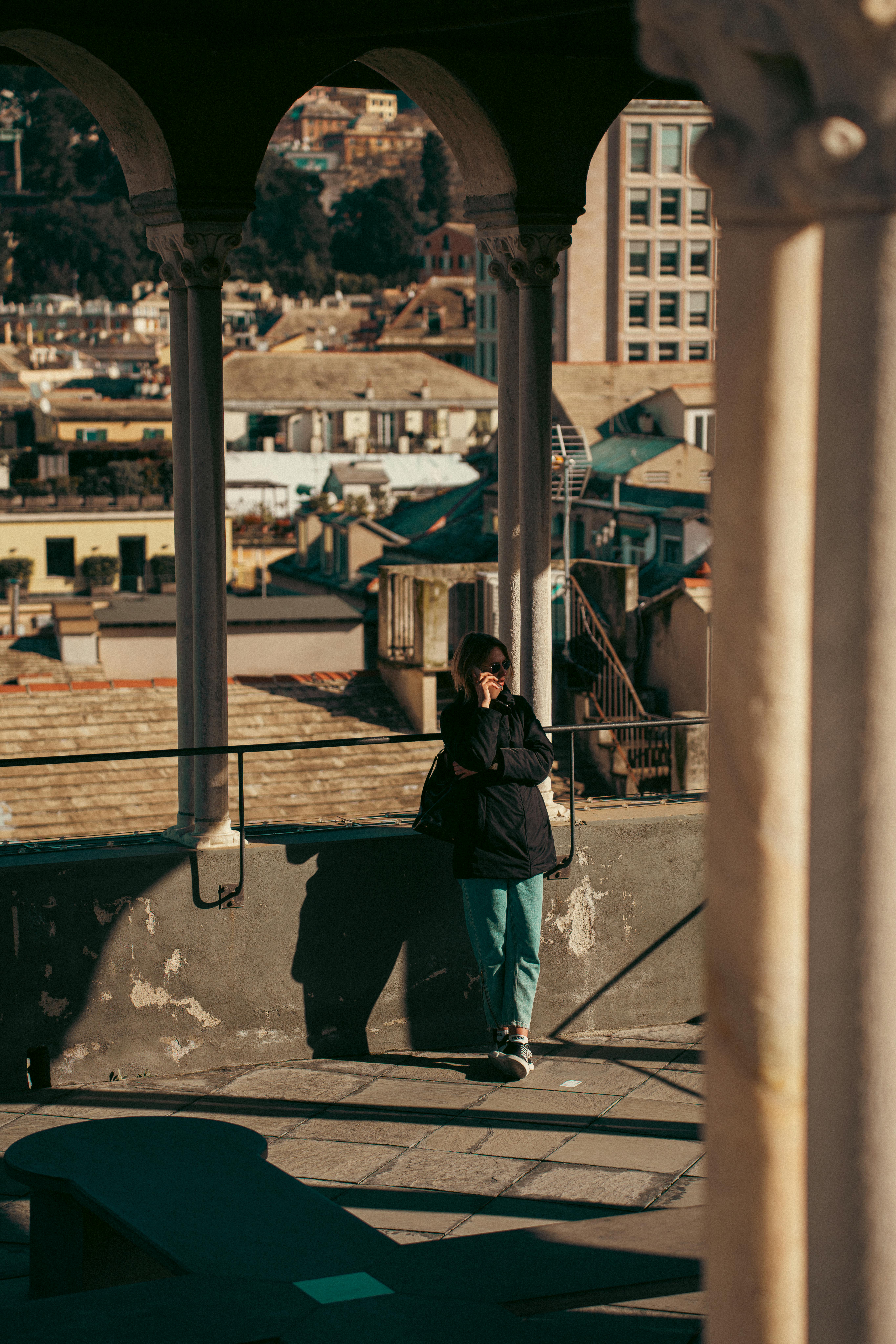 бесплатная Человек стоит под колоннами на террасе с видом на Геную, Италия. Стоковое фото