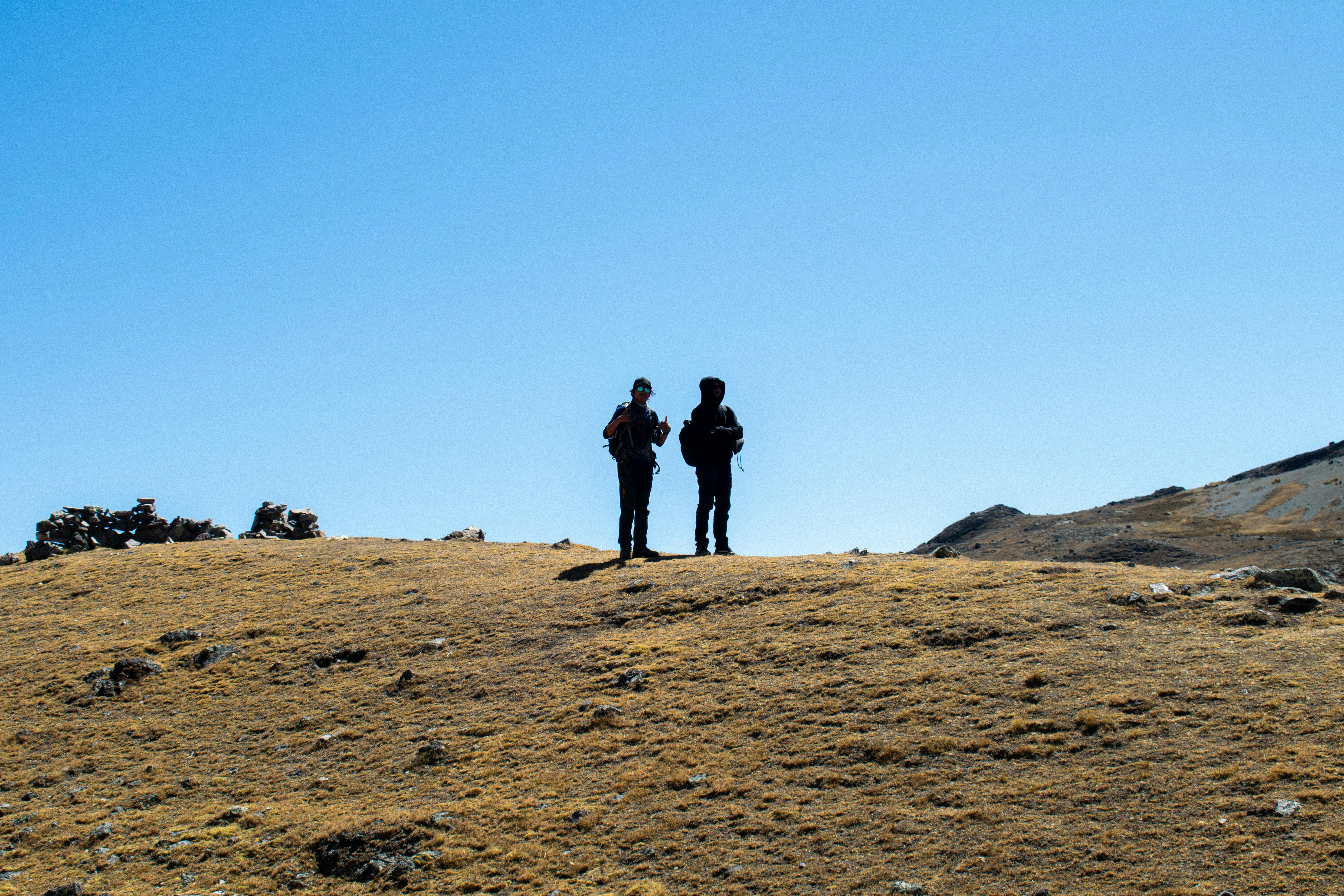 Gratis To vandrere i et ujævnt terræn i Cusco, Peru, mod en klar blå himmel. Lagerfoto