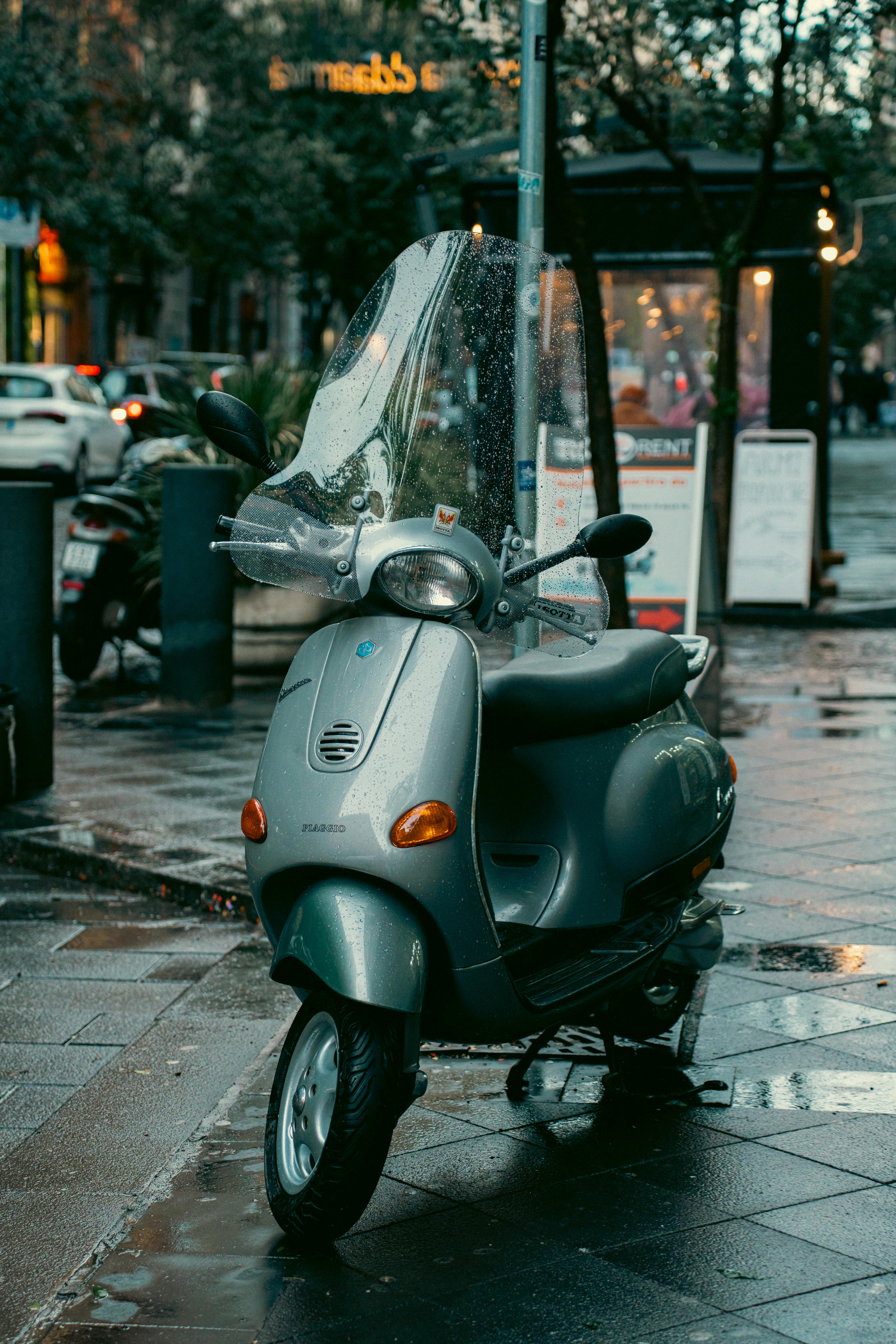 無料 イタリアのナポリの濡れた路上に駐車された象徴的なベスパ スクーター。雨上がりの都市生活を捉えています。 写真素材