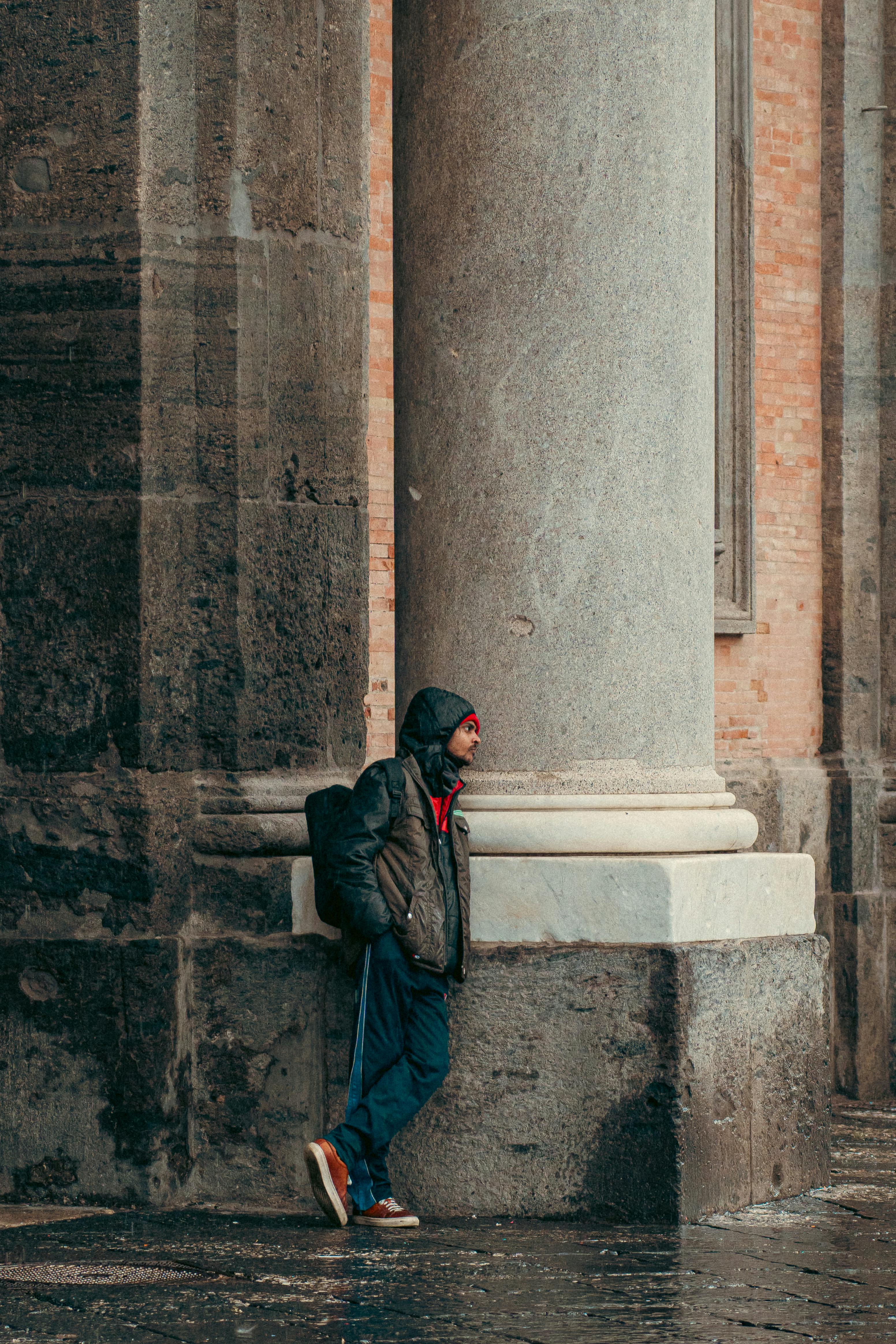 бесплатная Мужчина в повседневной одежде опирается на большую каменную колонну в Неаполе, Италия. Стоковое фото