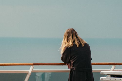 Free A woman stands on a cruise ship deck gazing at the tranquil sea in Naples, Italy. Stock Photo