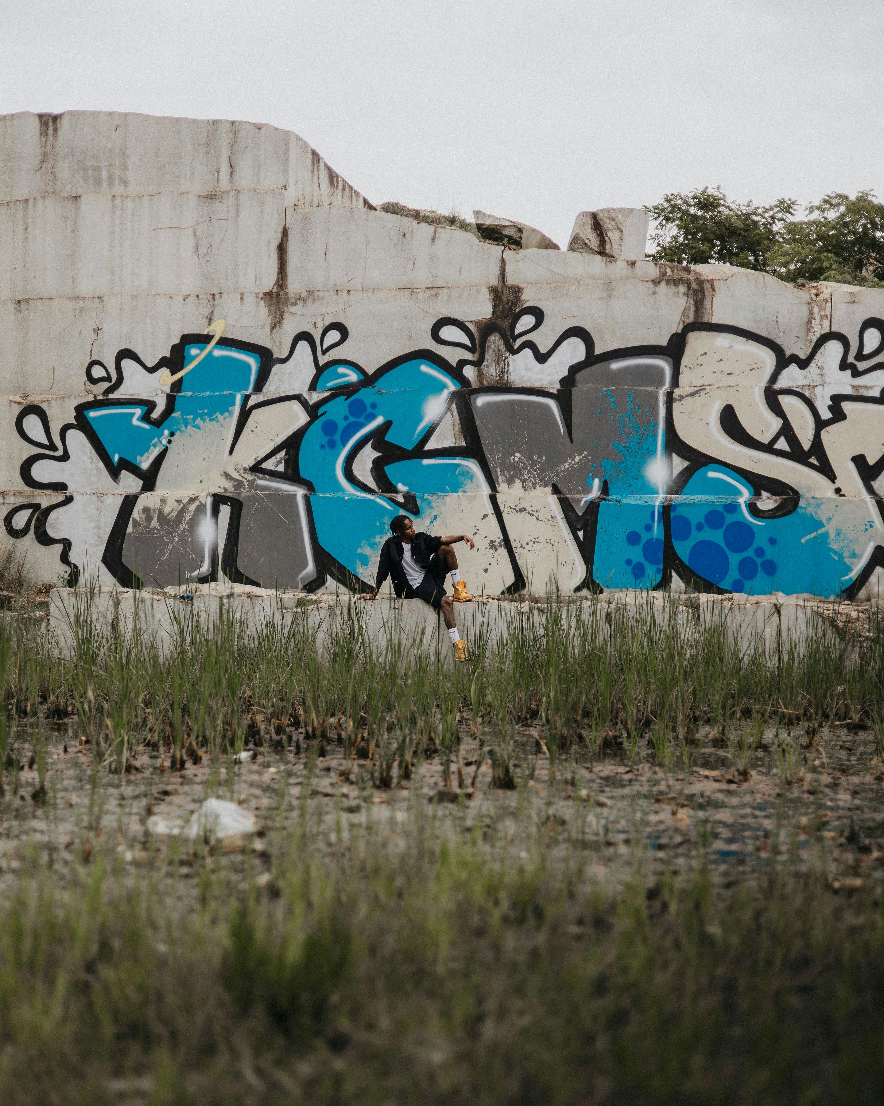 Zadarmo Graffiti na betónovej stene s osobou v jej blízkosti, ktoré predstavuje mestské pouličné umenie. Fotka z fotobanky