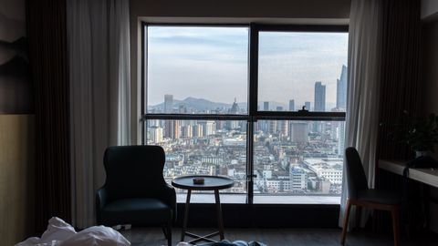 A stunning view of the city skyline from a cozy hotel room, showcasing urban architecture.