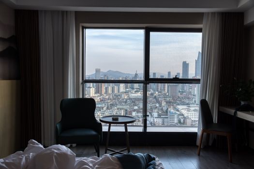 A stunning view of the city skyline from a cozy hotel room, showcasing urban architecture.