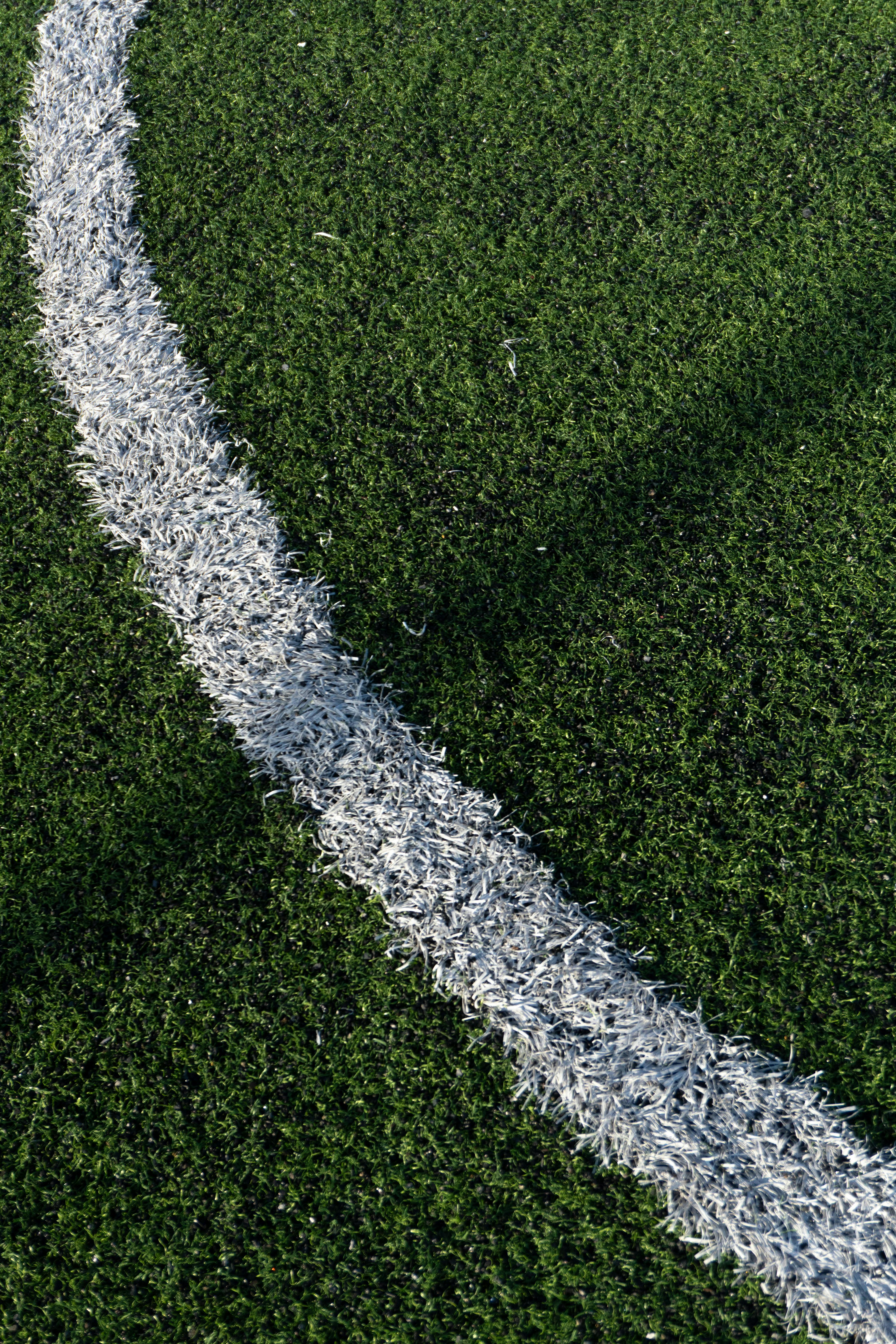 無料 トルコ、イスタンブールの緑の運動場に引かれた白い曲線のクローズアップ。スポーツや幾何学をテーマにした作品に最適です。 写真素材